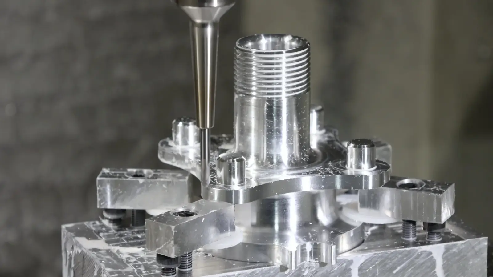 5-axis machining center milling a threaded aluminum housing in a custom fixture
